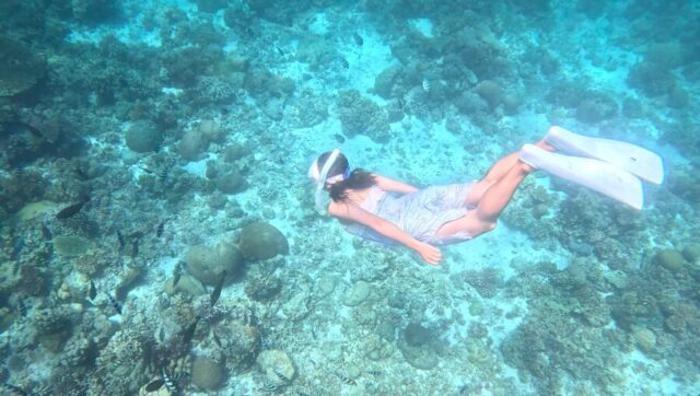 マクタン島の海でサンゴ礁の上をシュノーケリングする女性